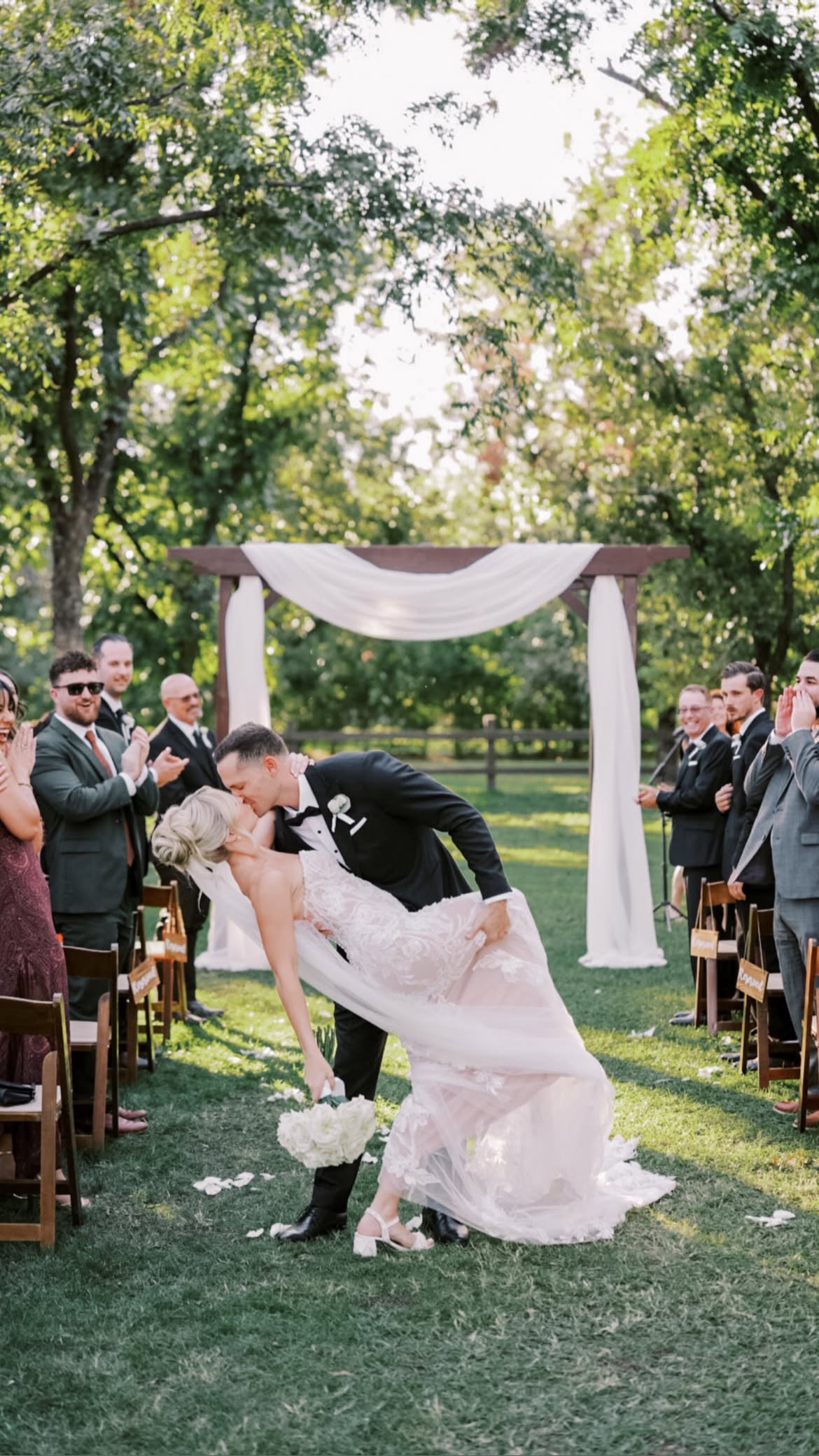 Groom dipping bride at outdoor garden wedding